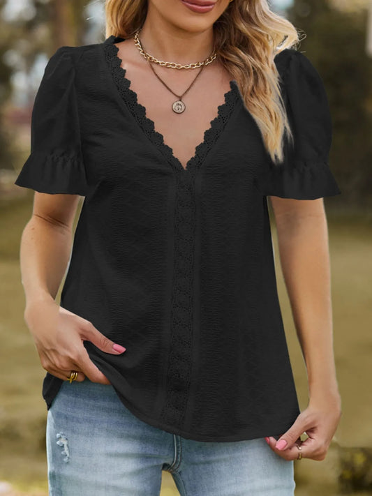 Woman wearing a black blouse with lace details and blue jeans outdoors.