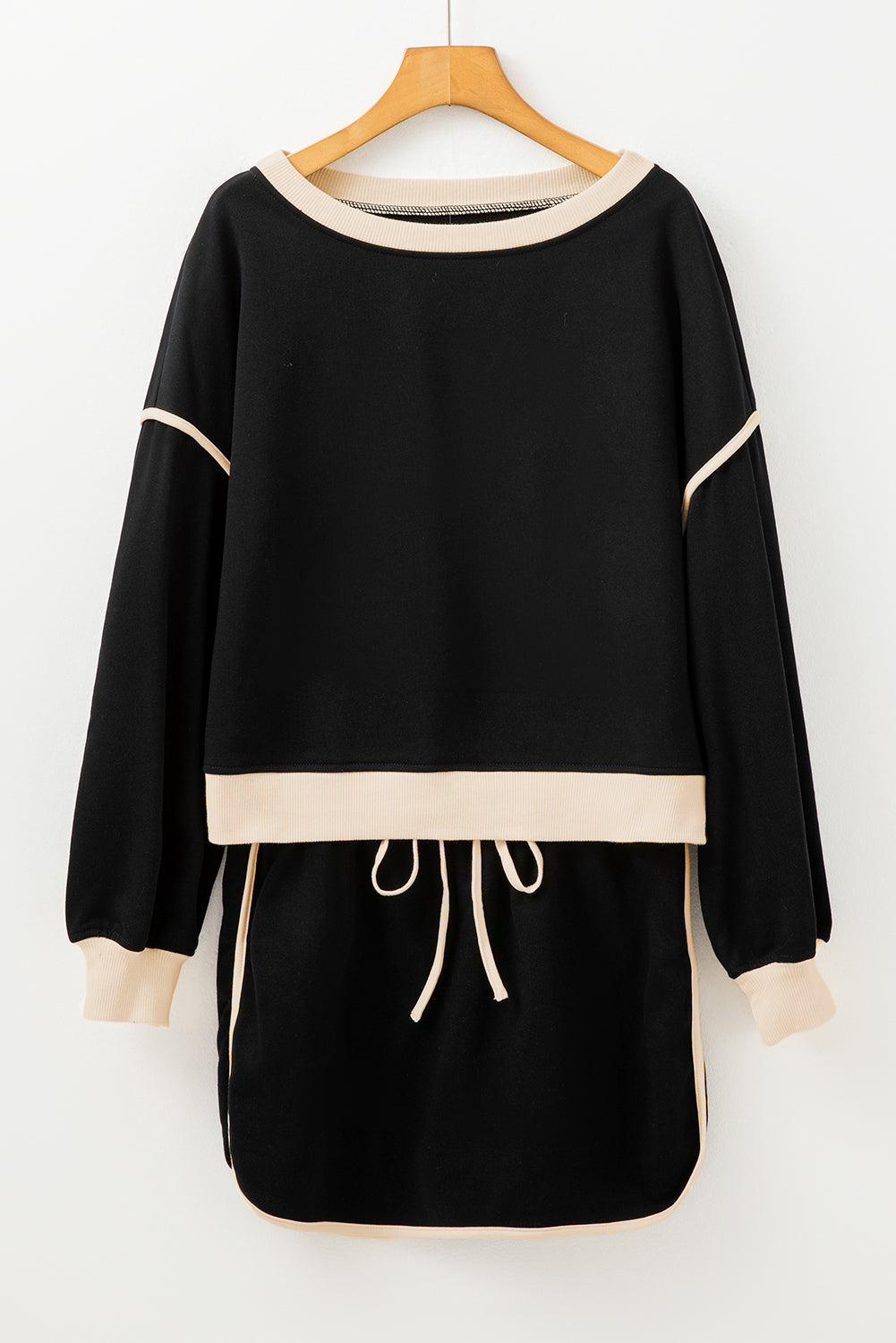 Black dress with beige accents on a hanger against a white background