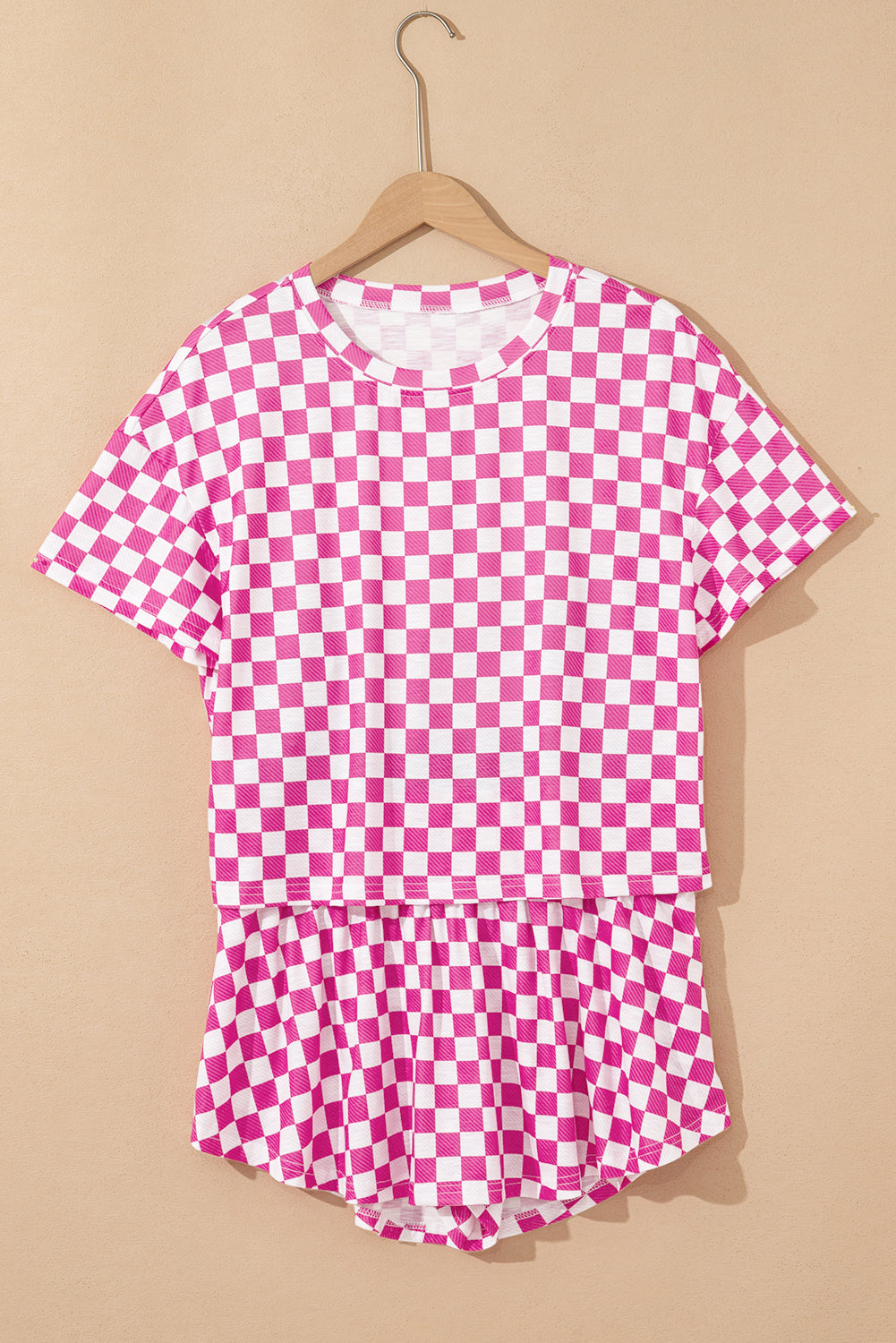 Pink and white checkered shirt on a hanger against a beige background