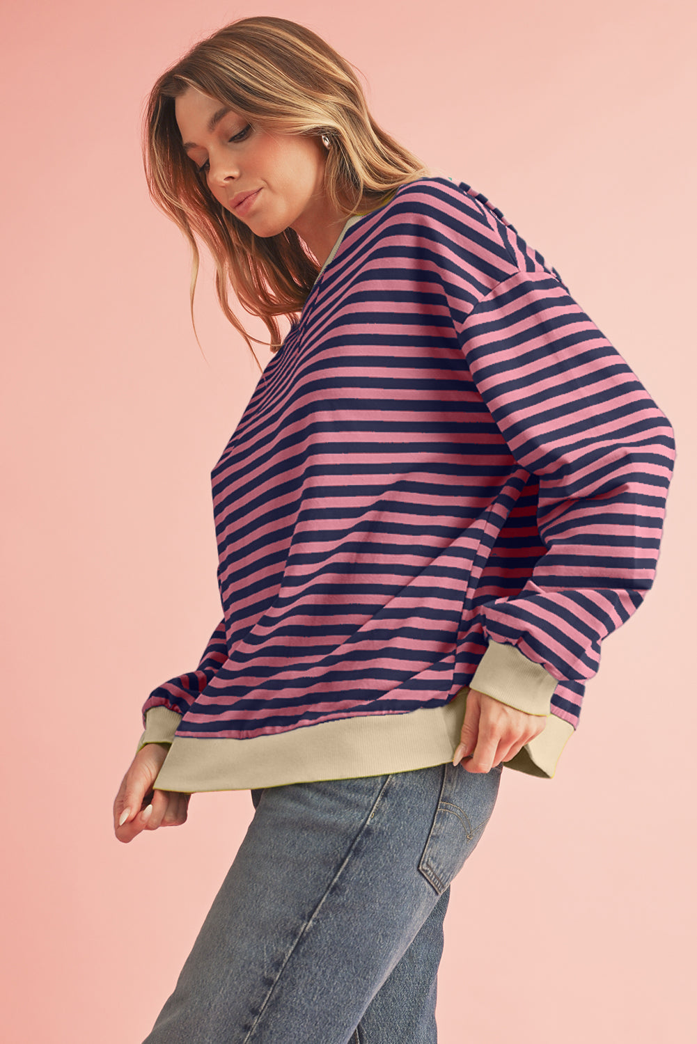 Woman wearing a striped sweater and jeans on a pink background