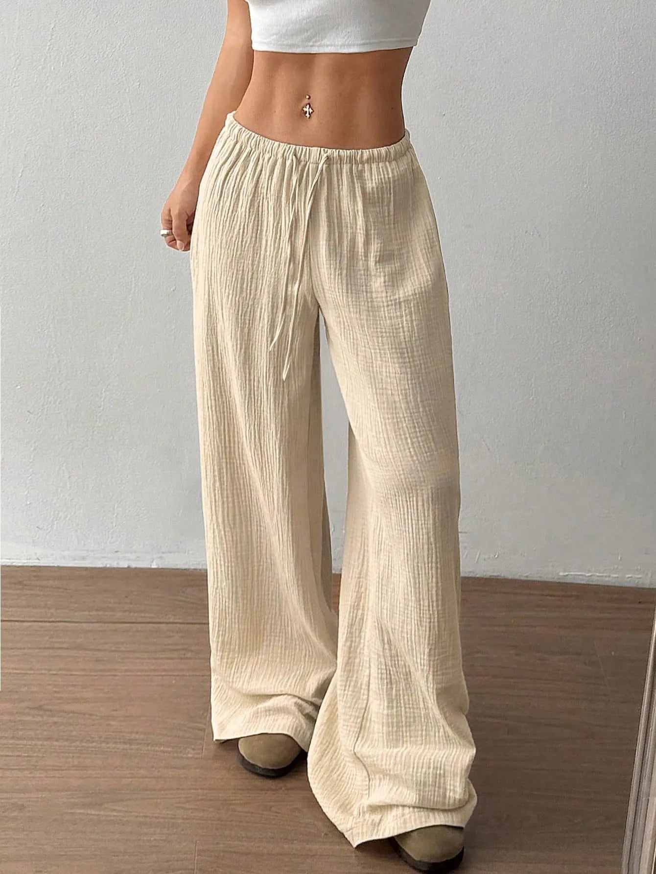 Person wearing beige wide-leg pants against a plain background