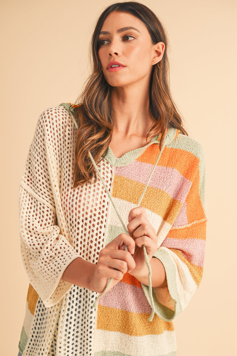 Woman wearing a colorful striped sweater against a beige background