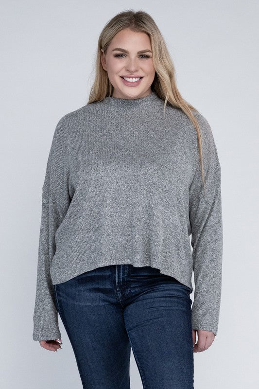 Woman wearing a gray sweater and blue jeans against a white background