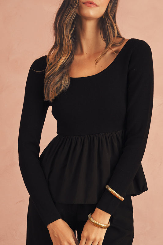 Black long-sleeve dress worn by a person on a pink background