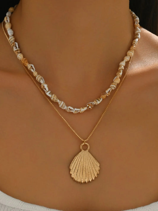 Necklace with shell pendant and beaded chain on a person's neck