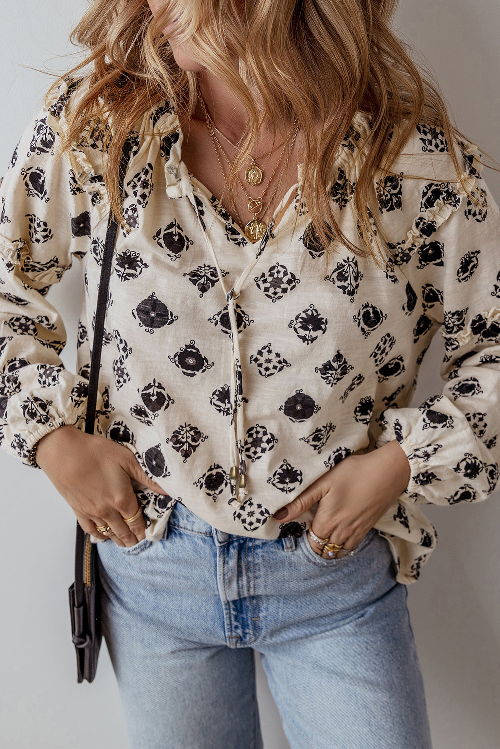 Person wearing a floral blouse and jeans with a neutral background