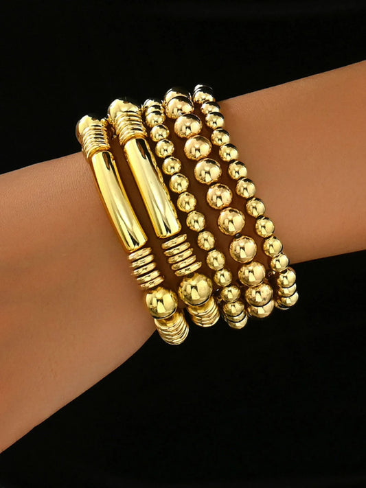 Gold beaded bracelets on a wrist against a black background