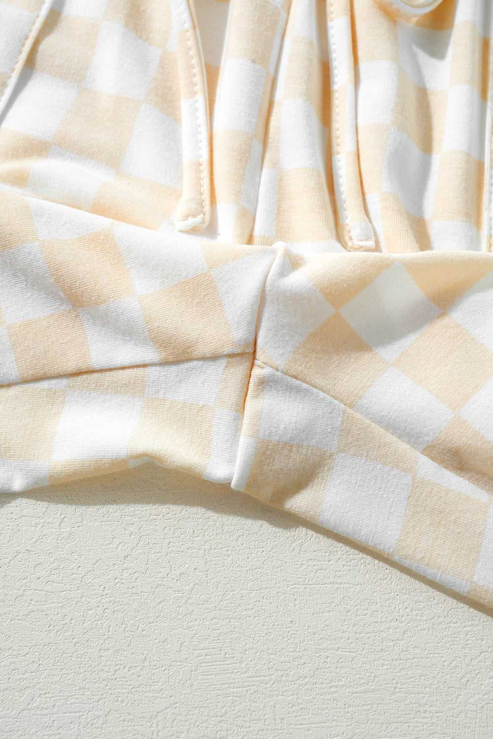 Close-up of a beige and white checkered fabric on a light gray background