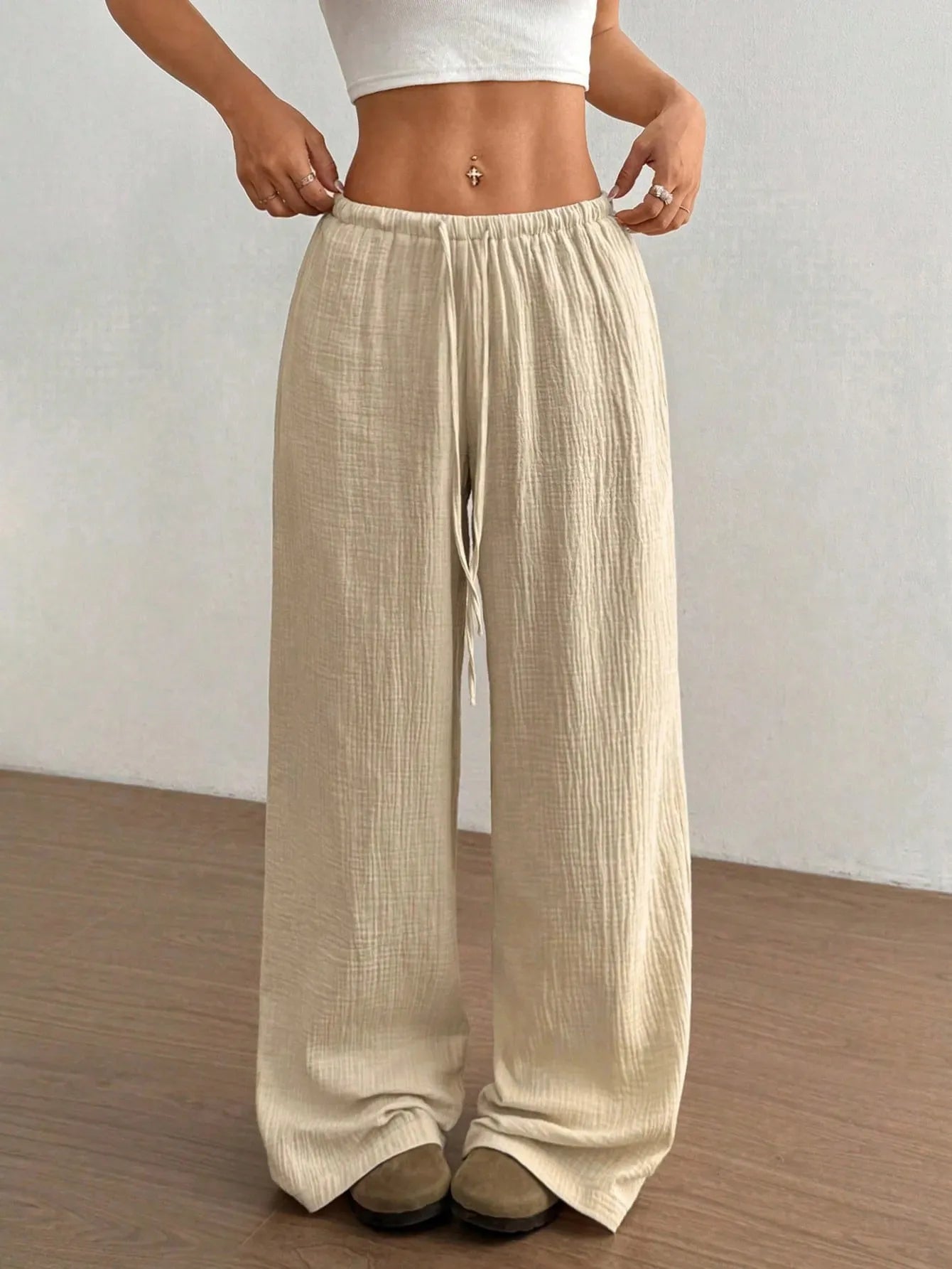 Person wearing beige wide-leg pants against a plain background