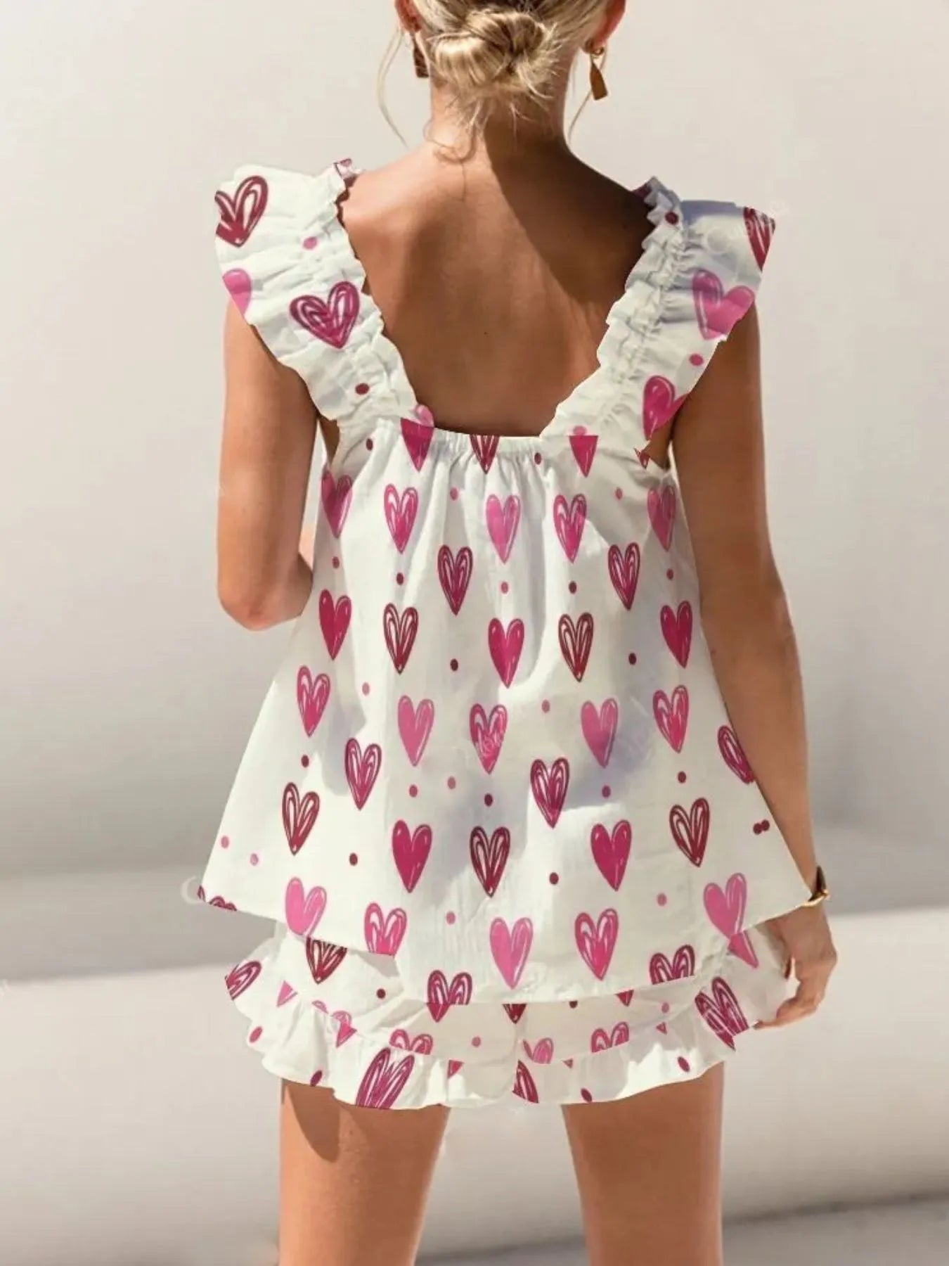 White dress with pink heart patterns on a plain background