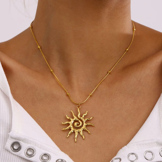 Gold sun-shaped pendant necklace on a person wearing a white top with decorative buttons.