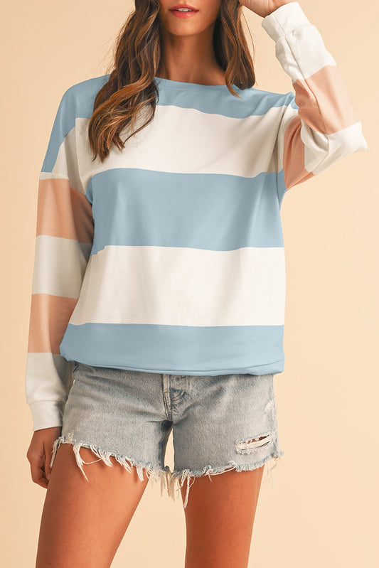 Person wearing a striped sweater and denim shorts on a beige background