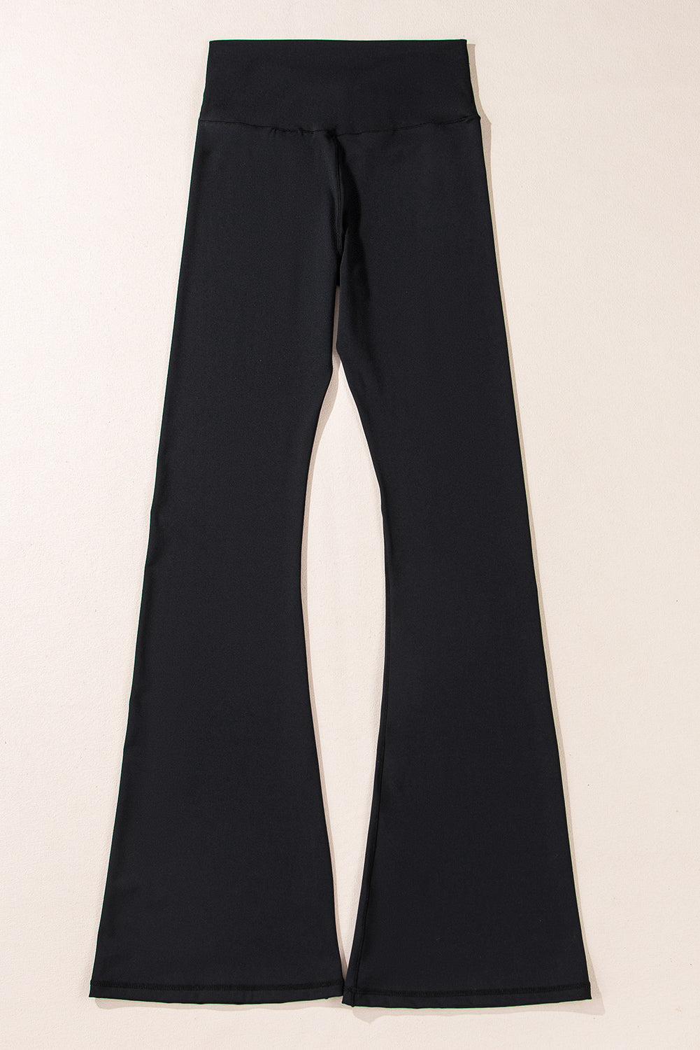 Black bell-bottom pants on a light beige background