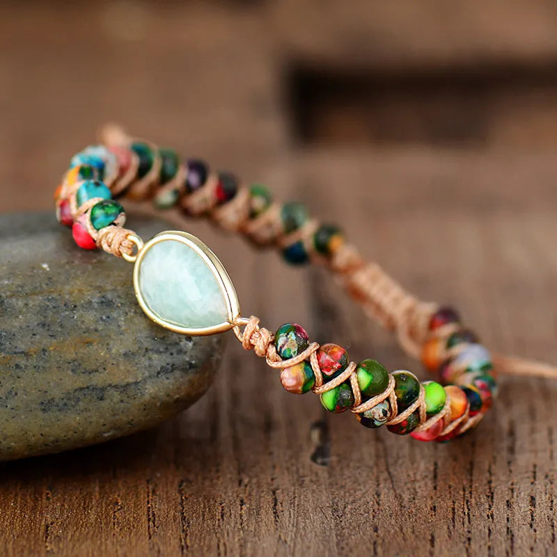 Colorful beaded bracelet with a large green stone on a wooden surface
