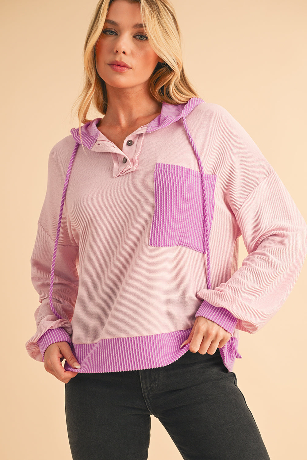Woman wearing a pink and purple sweater with a beige background