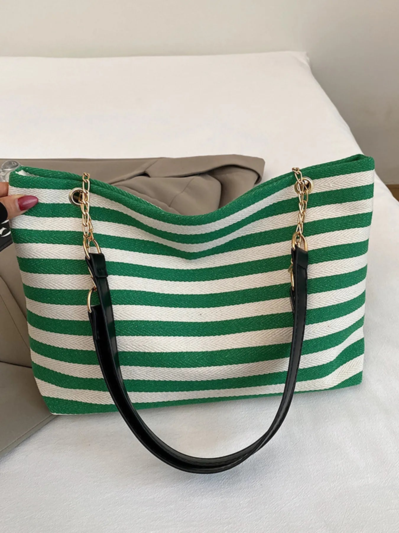 Green and white striped tote bag with black handle on a light background