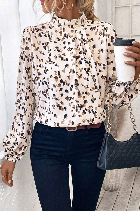 Person wearing a patterned blouse and dark jeans, holding a coffee cup and a handbag.