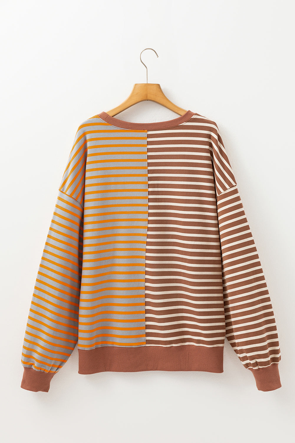 Striped sweater with yellow and brown horizontal stripes on a hanger against a white background