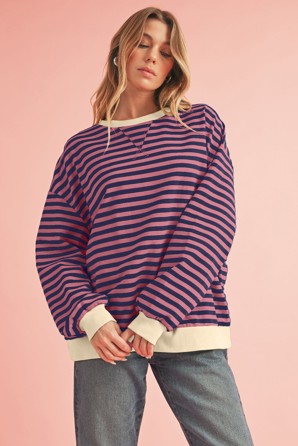 Woman wearing a striped sweater with a pink background