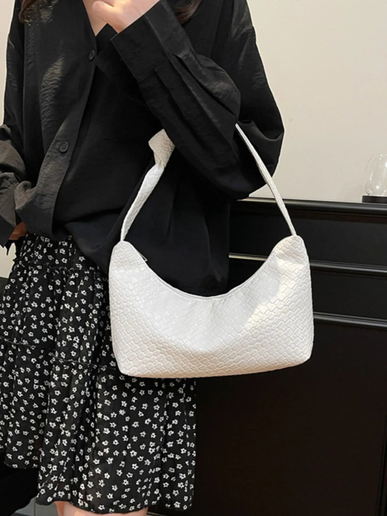 Person holding a white textured handbag against a neutral background