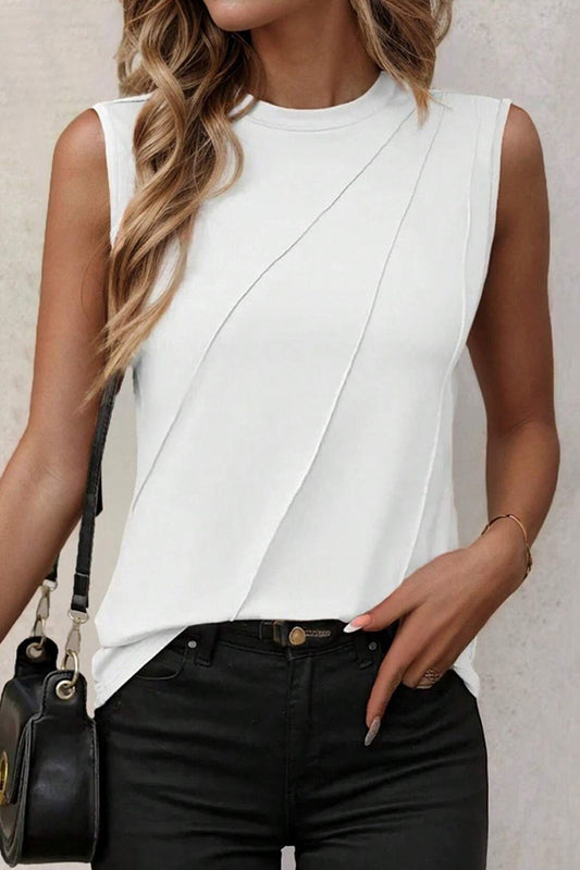 Woman wearing a white sleeveless top and black pants, holding a black handbag.