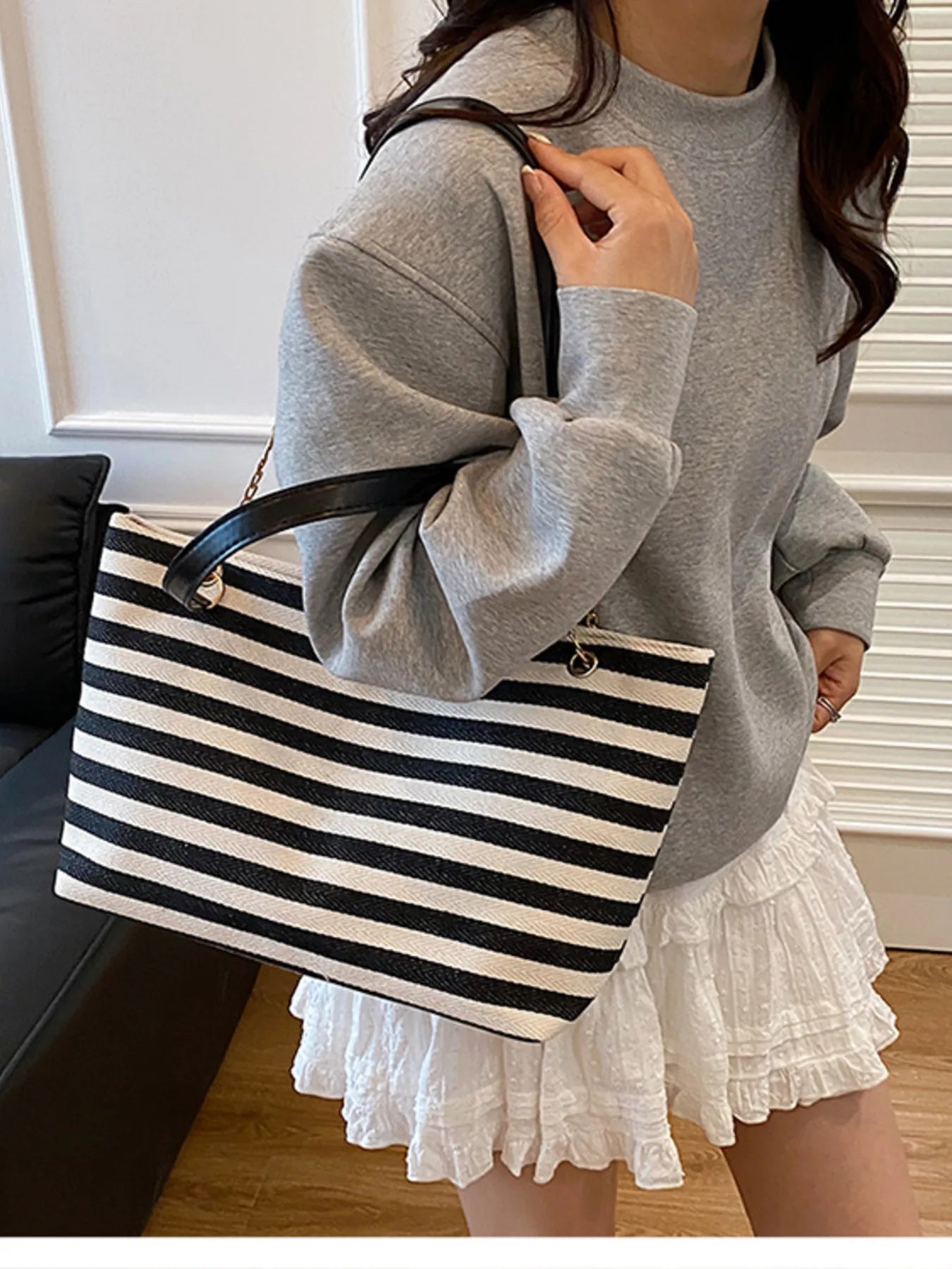 Person holding a black and white striped bag in a casual setting