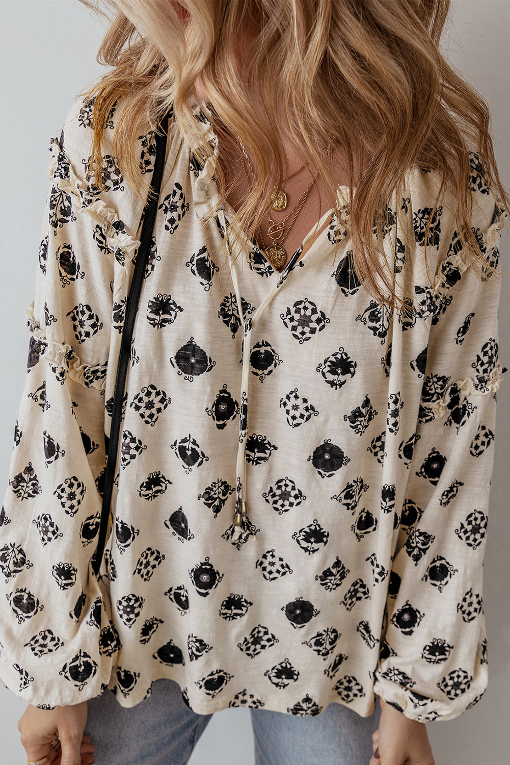 Person wearing a floral blouse with black patterns on a neutral background