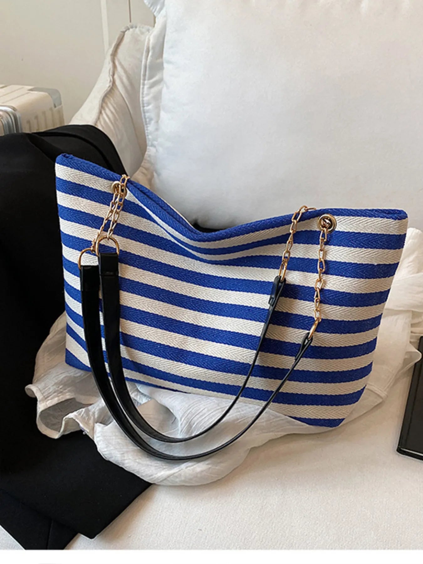 Blue and white striped tote bag with black handles on a white surface
