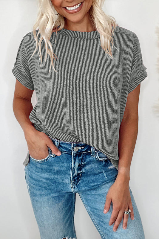 Woman wearing a gray ribbed t-shirt and blue jeans against a white background