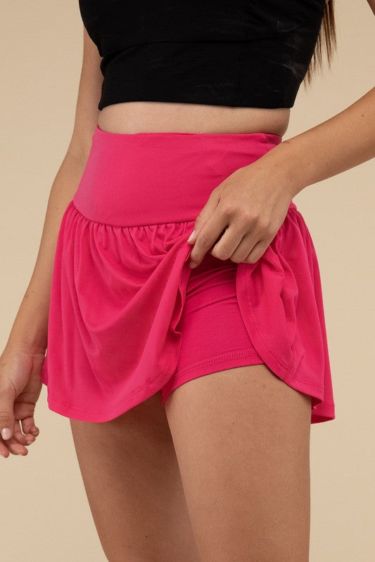 Person wearing a black top and bright pink skirt on a beige background