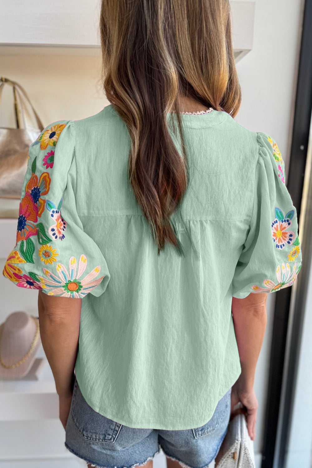 Person wearing a green top with floral sleeves in a kitchen setting
