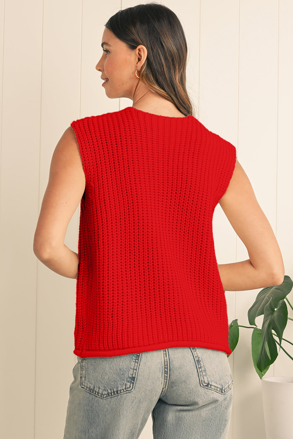 Woman wearing a red sleeveless knitted top with a neutral background