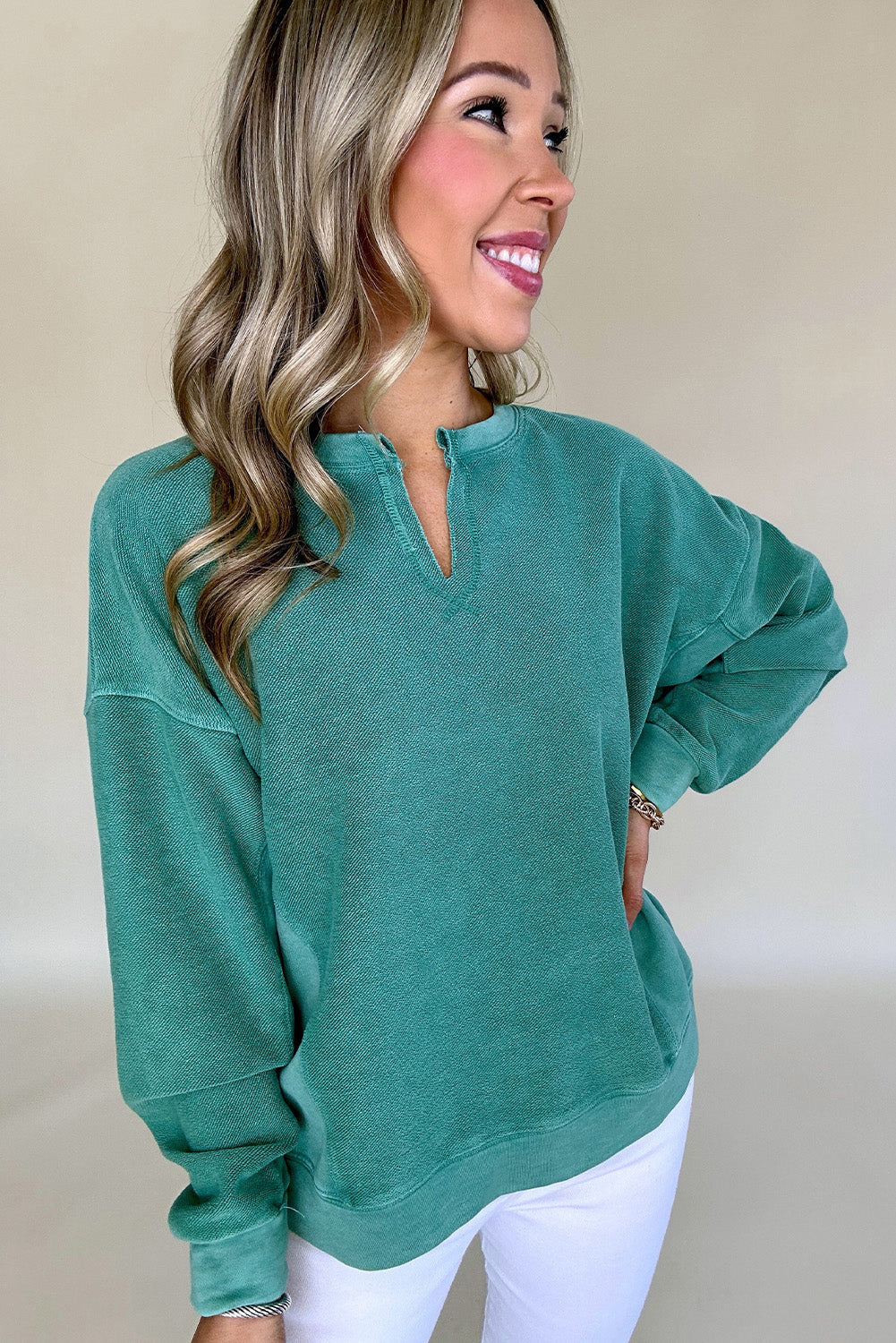 Woman wearing a teal sweater against a plain background