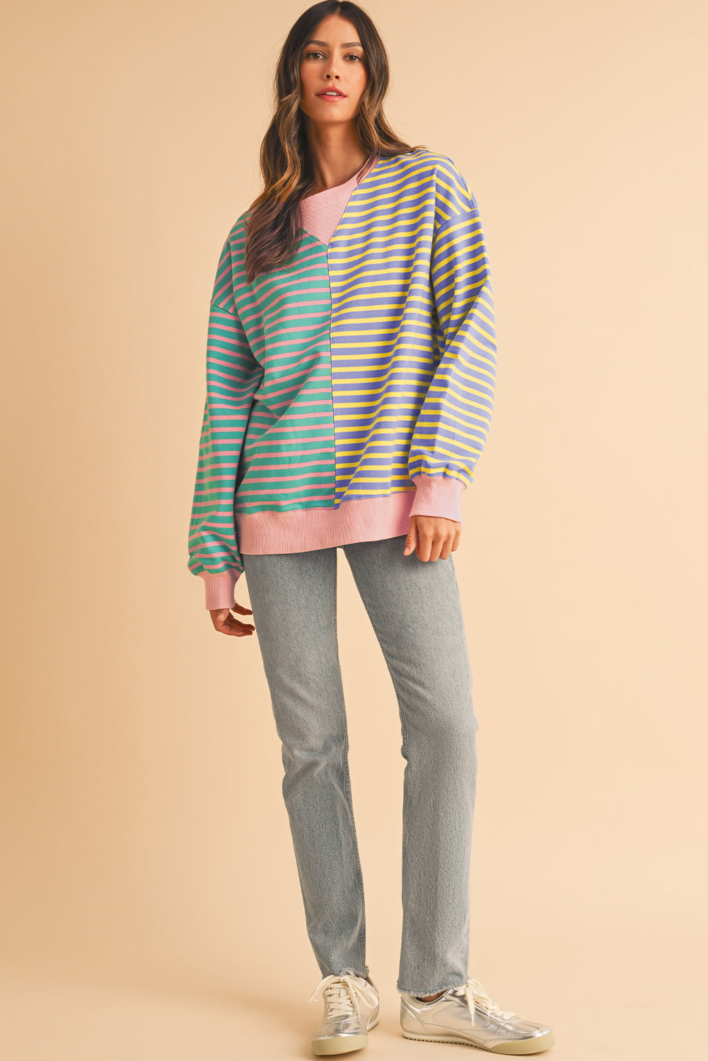 Woman wearing a striped sweater and jeans on a beige background
