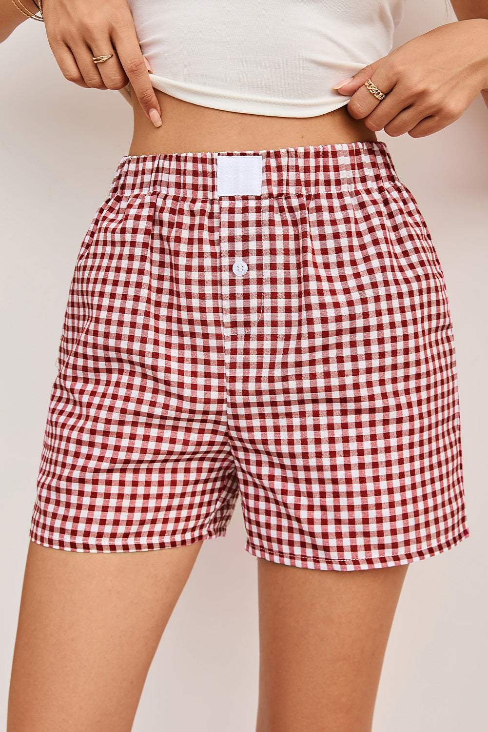 Red and white checkered shorts worn by a person on a plain background