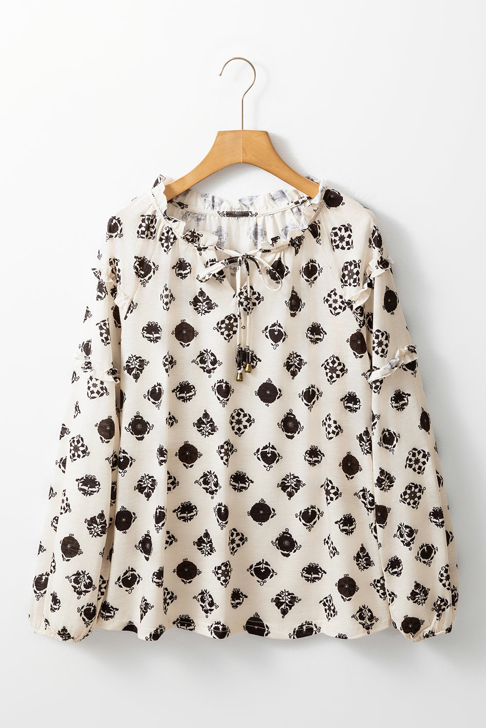 Floral patterned blouse on a wooden hanger against a white background
