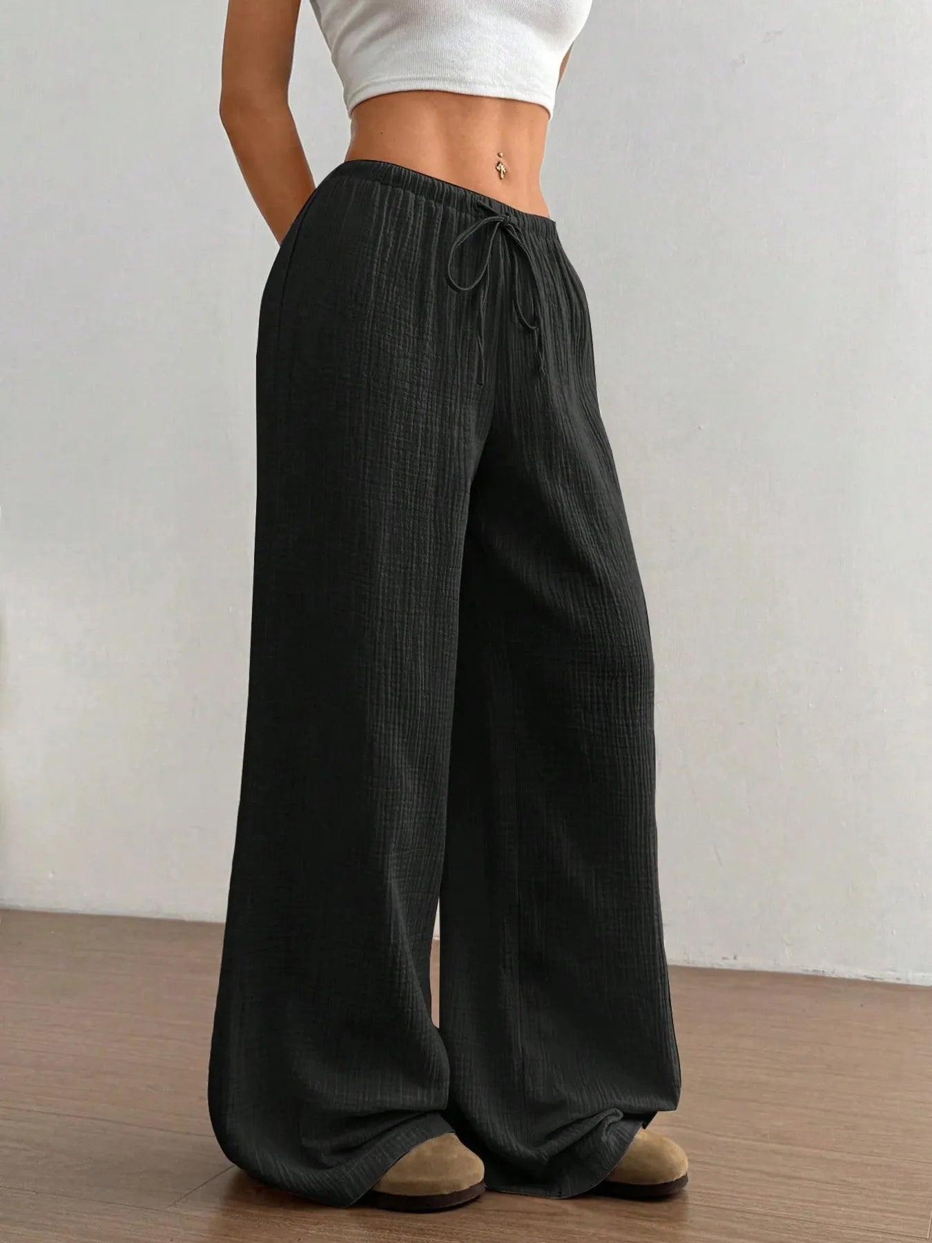 Person wearing black wide-leg pants with a plain background