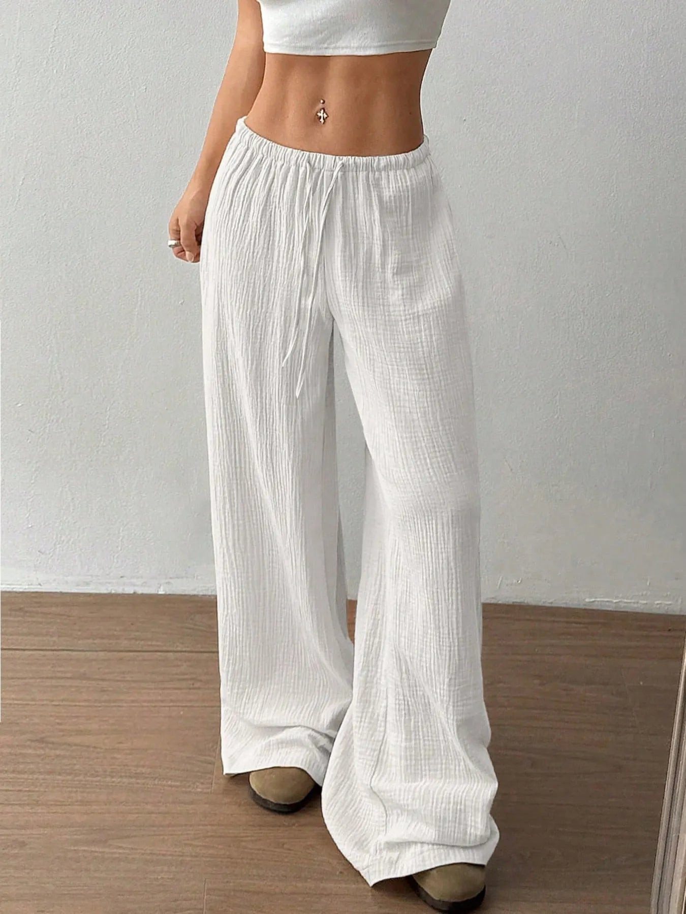 Person wearing white wide-leg pants against a plain background