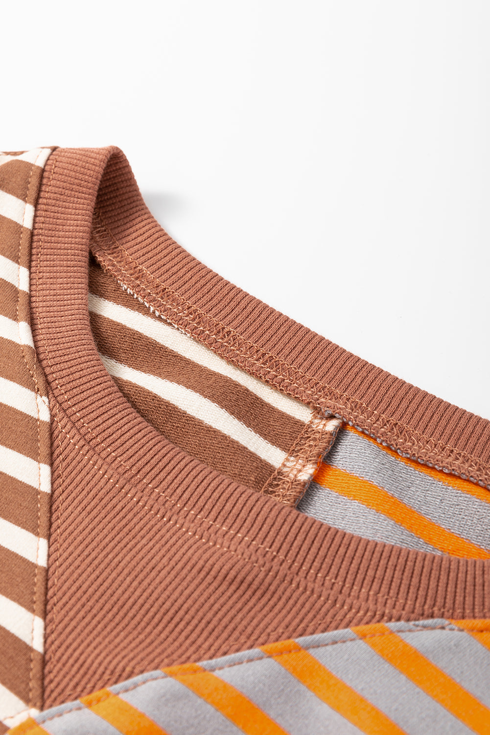 Close-up of a striped fabric with brown, white, orange, and gray colors on a white background.