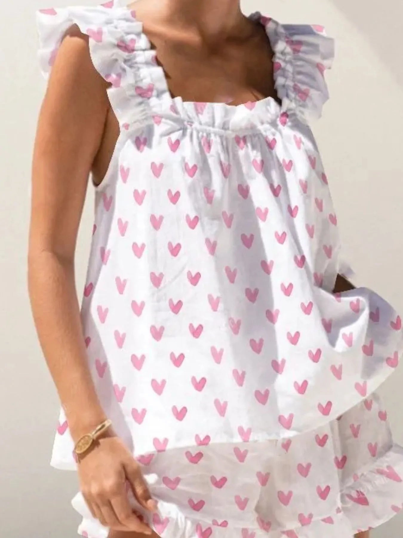 White dress with pink heart patterns worn by a person.
