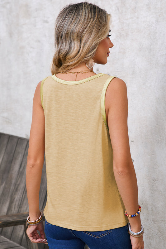 Woman wearing a beige sleeveless top and blue jeans against a neutral background