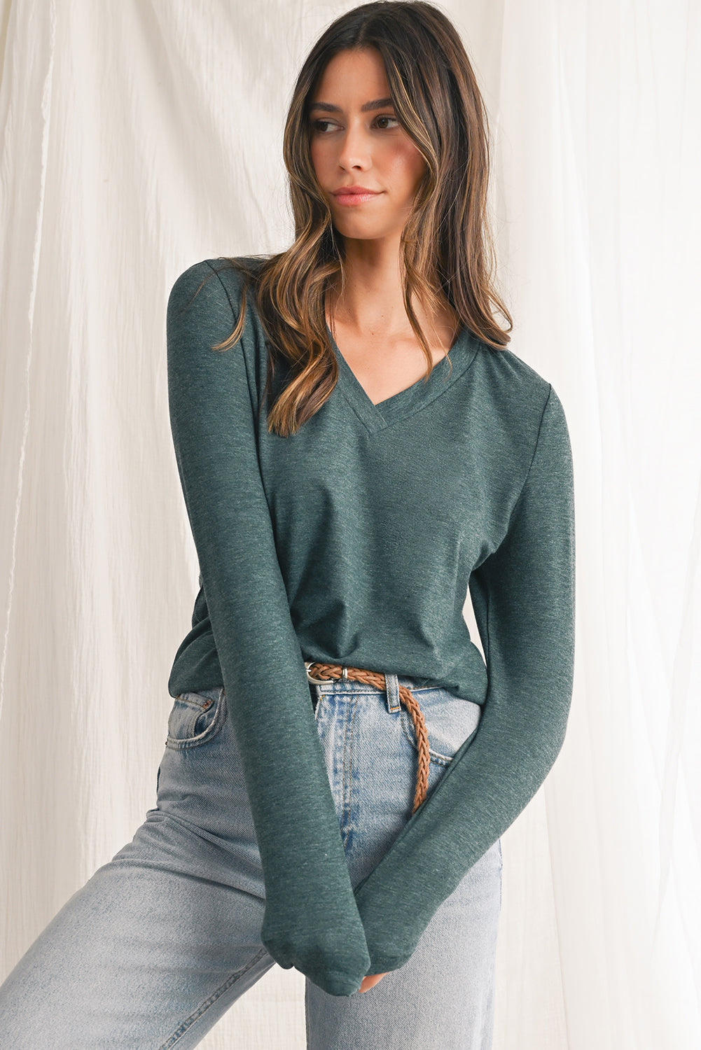 Woman wearing a green sweater and jeans against a white background