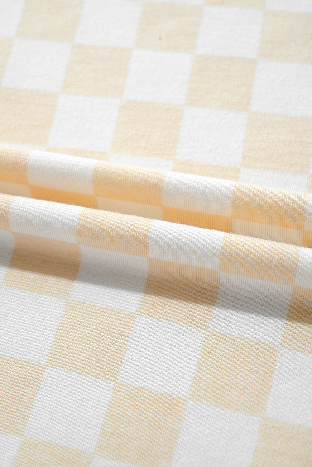 Close-up of a checkered fabric with light yellow and white squares.