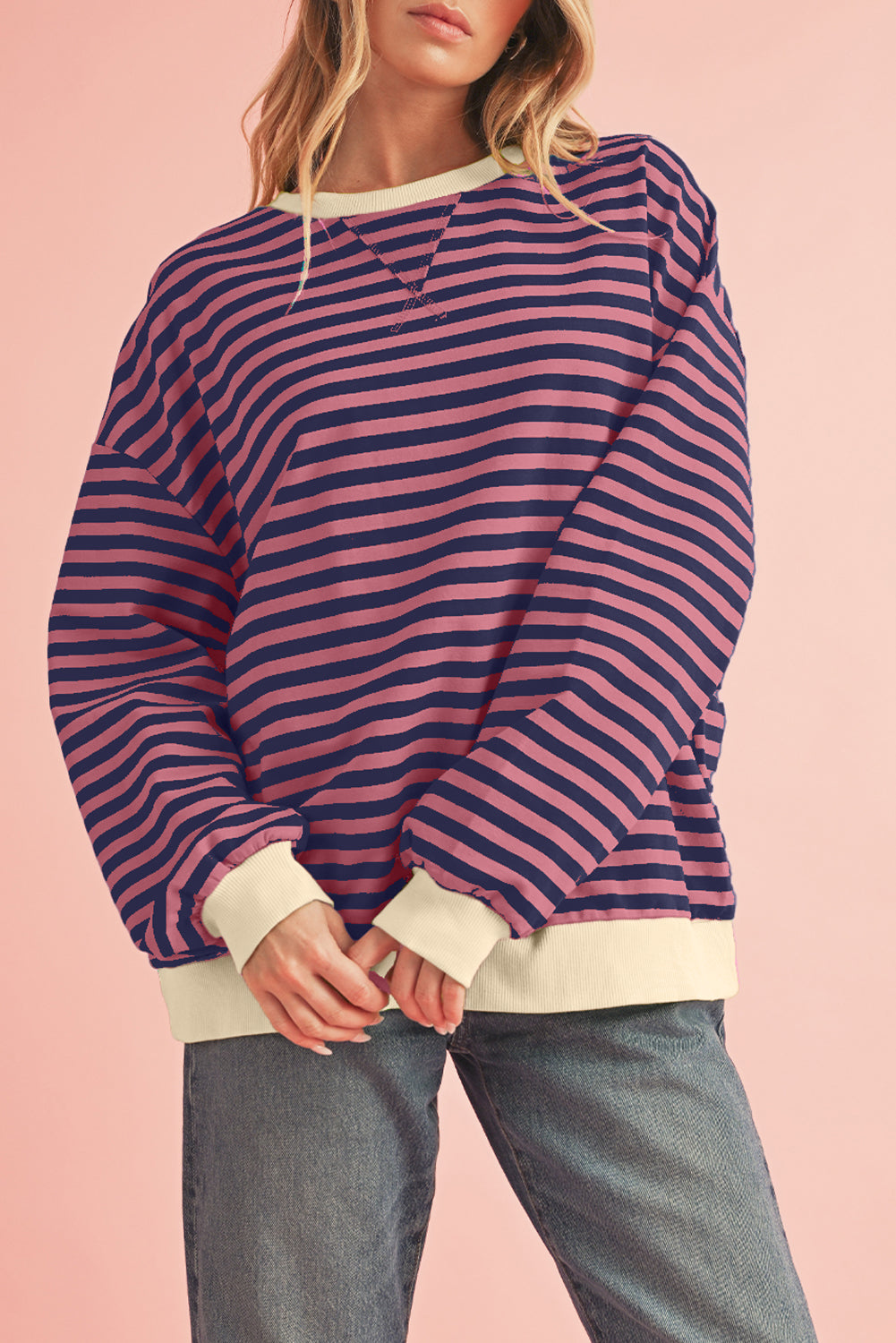 Person wearing a striped sweater with a pink background