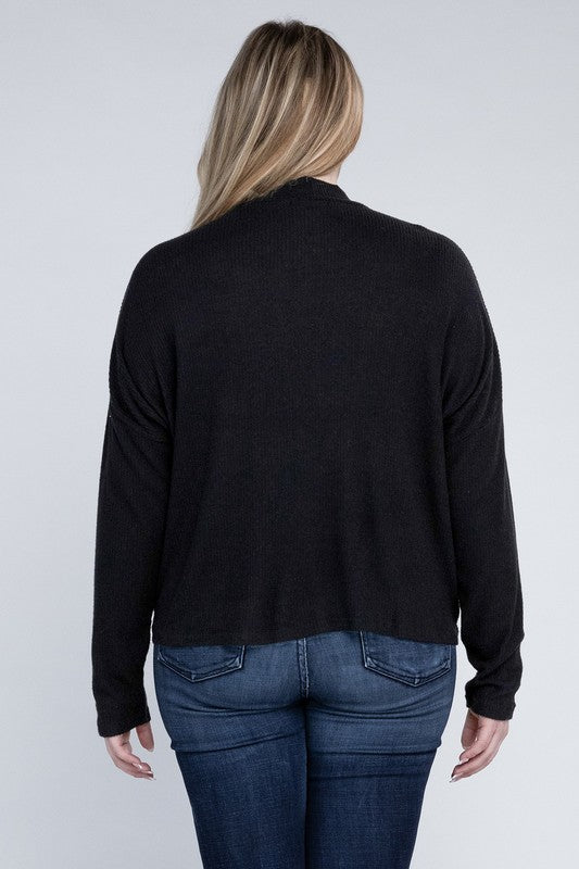 Person wearing a black long-sleeve top and blue jeans on a white background