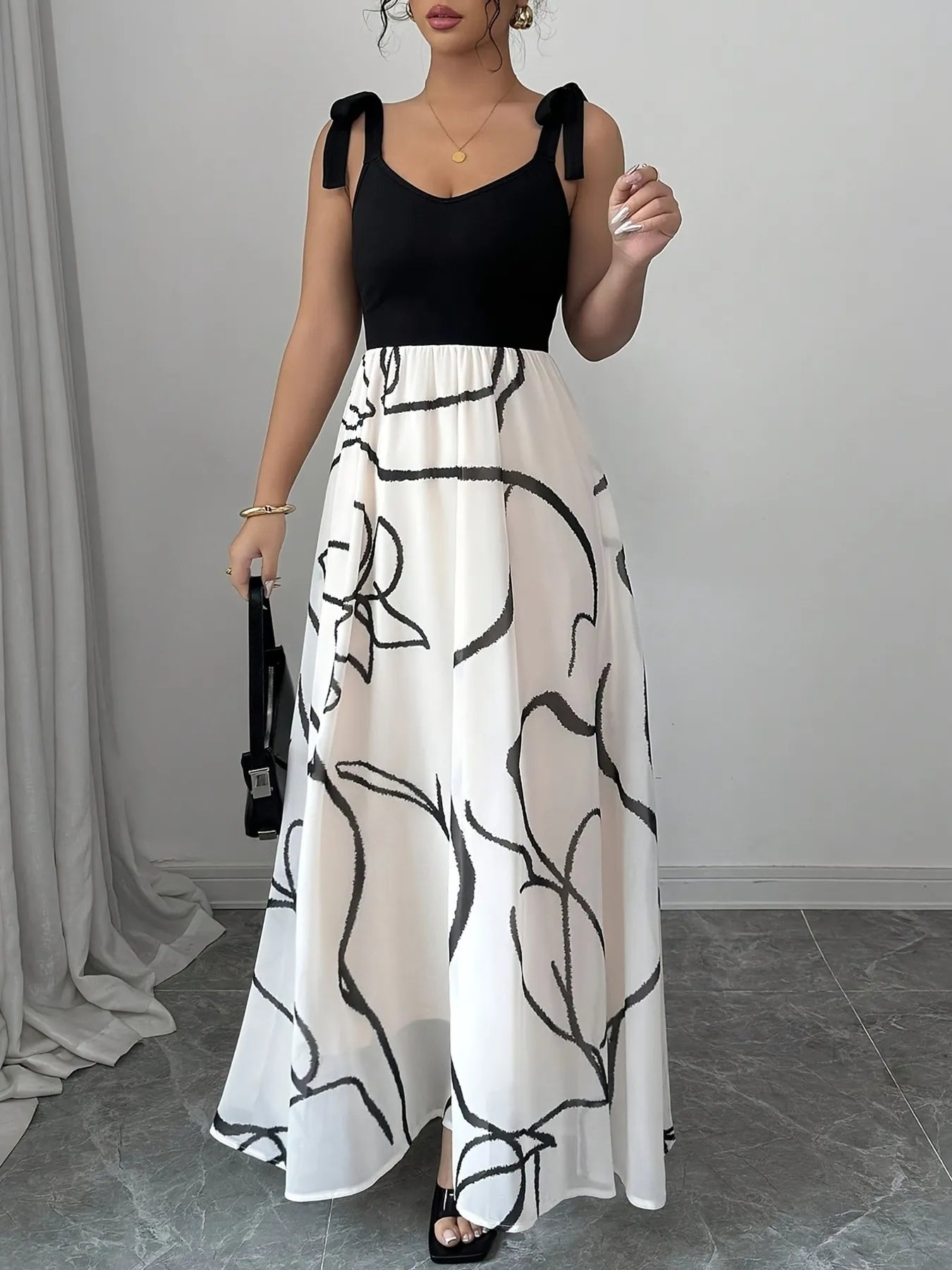 Woman wearing a black top and white floral dress against a plain background