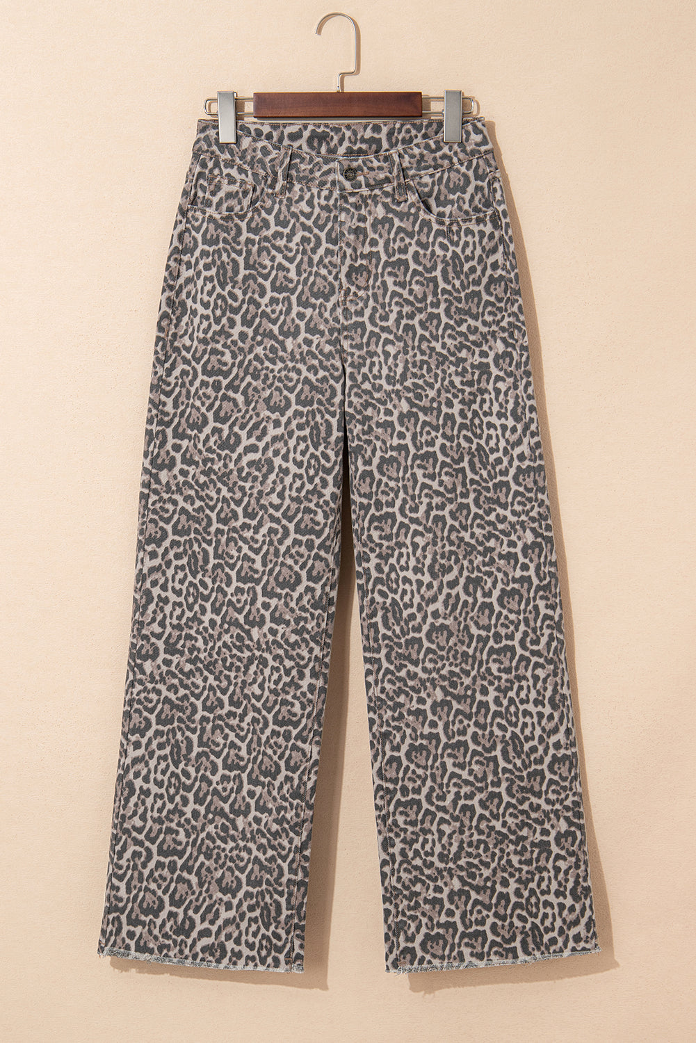 Leopard print pants on a hanger against a beige background
